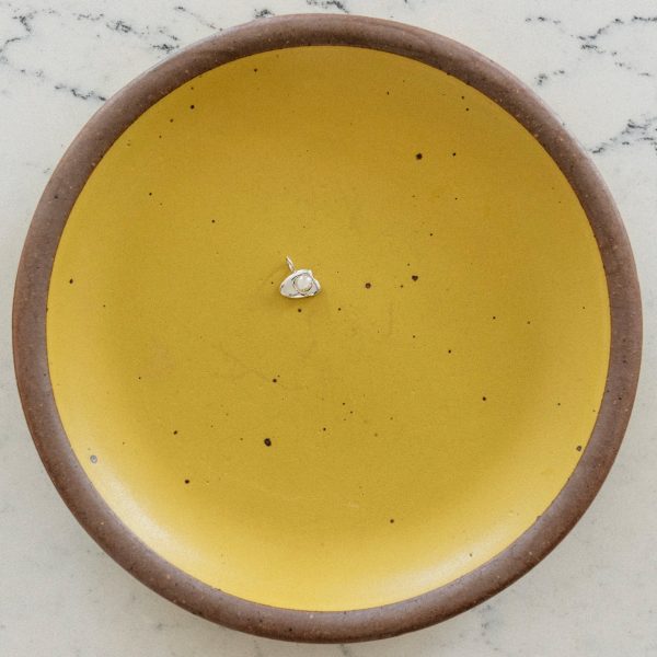 sterling silver egg charm on a yellow plate