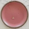 14k gold egg charm on a pink plate