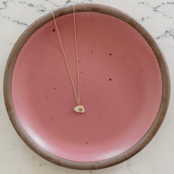 14k gold egg charm on a pink plate