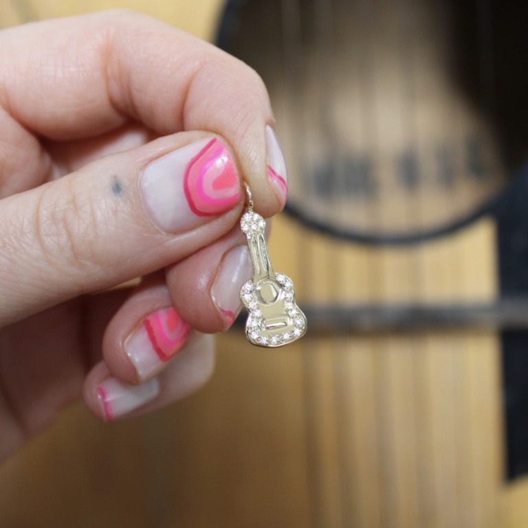 close up holding the gold diamond guitar charm