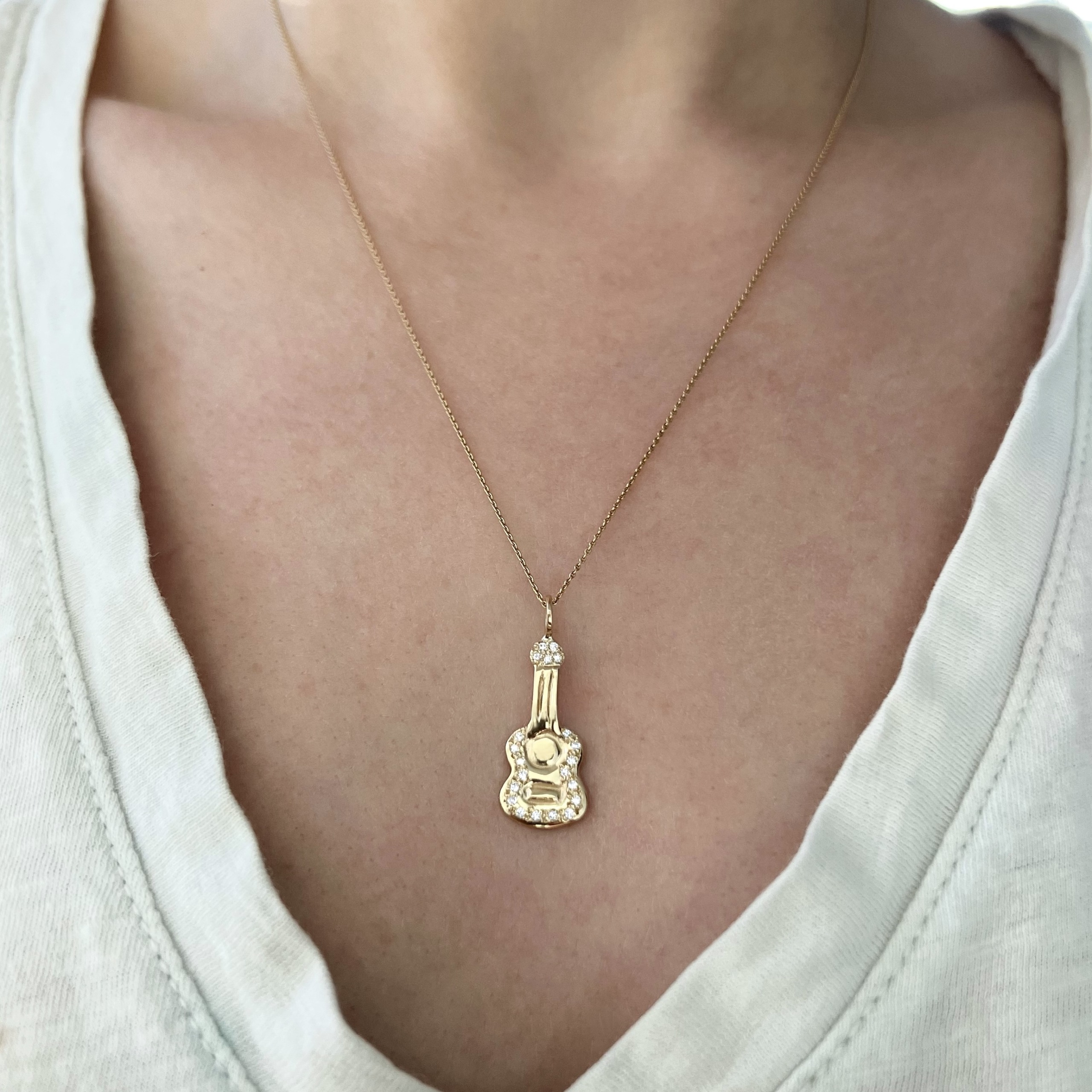 wearing the gold diamond guitar charm on a necklace