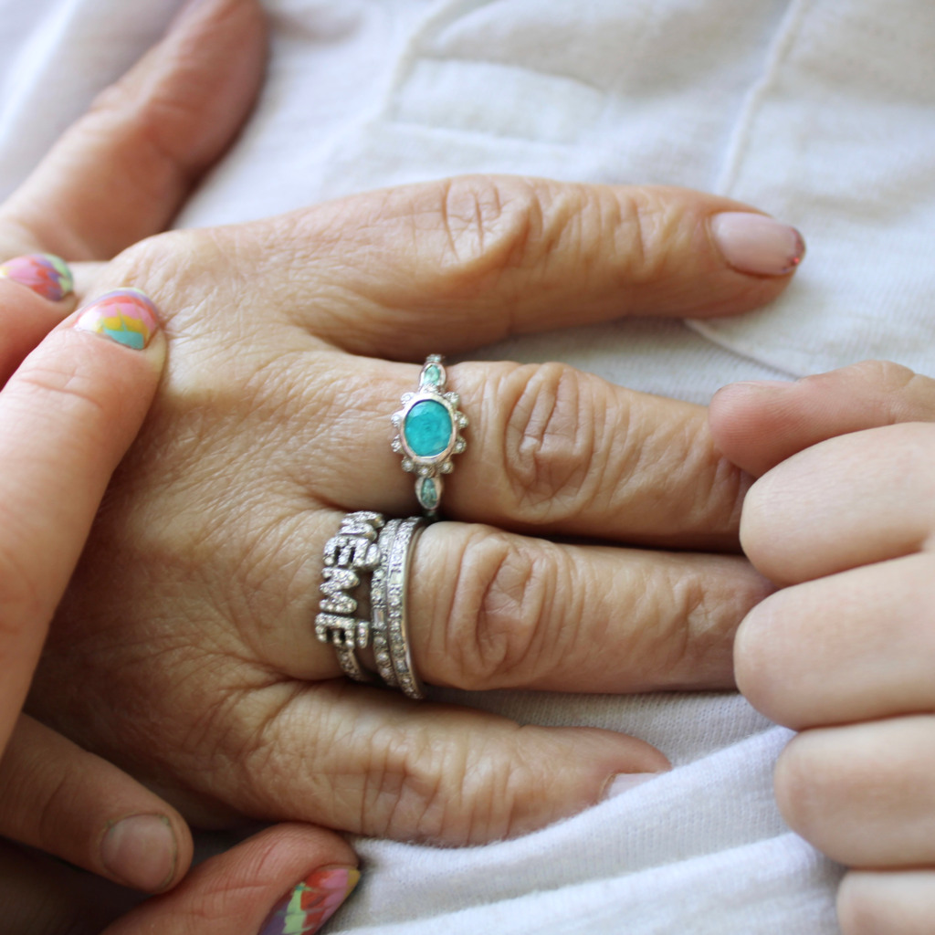 Close-up holding Grandma's hand wearing the new grandma wearing the new paraiba tourmaline flower ring and other rings