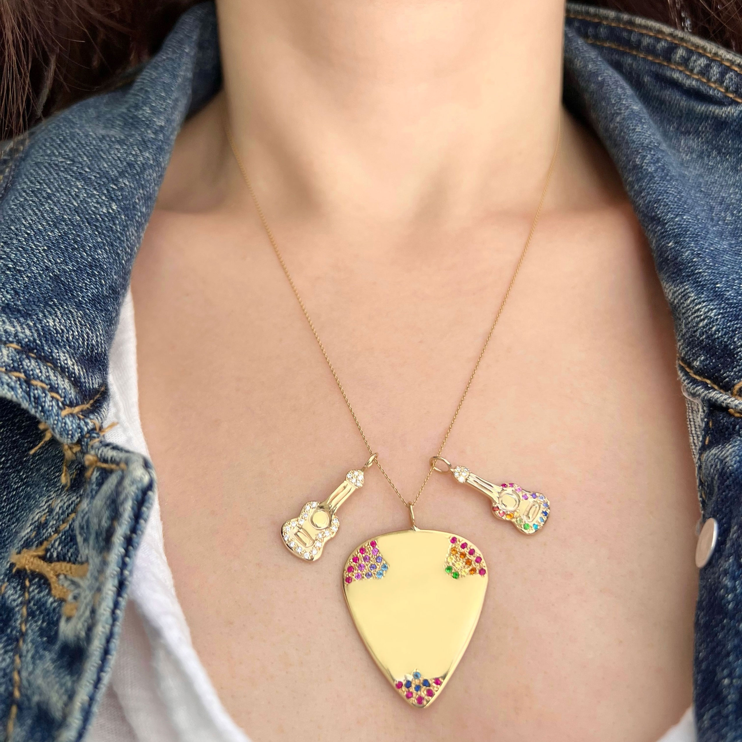 Wearing a necklace with the new rainbow colored gemstone 14k yellow gold guitar charm, the rainbow colored 14k yellow gold guitar pick charm, and another 14k yellow gold guitar charm with white diamonds