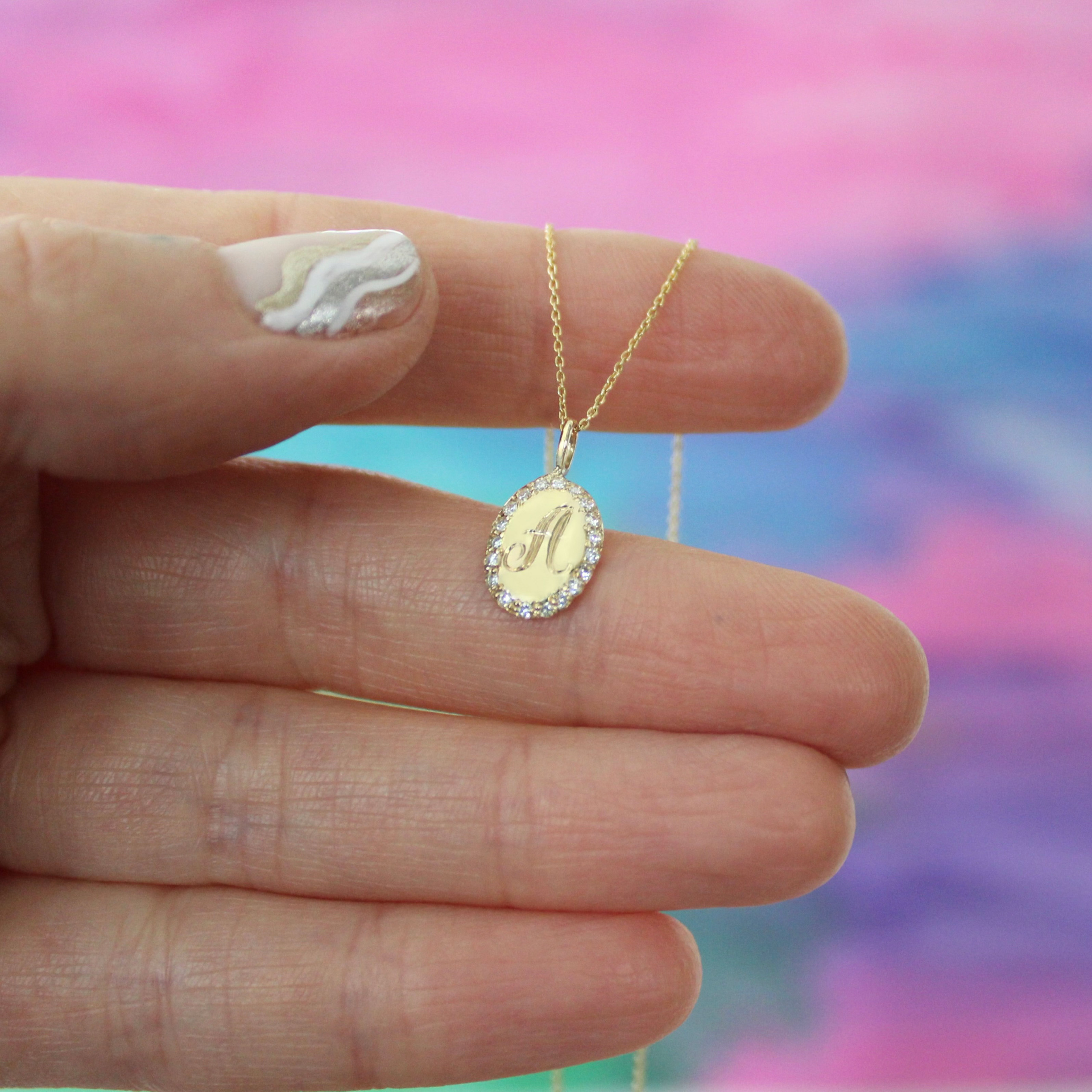 Close-up holding the Oval Charm Necklace, 14k yellow gold, diamonds