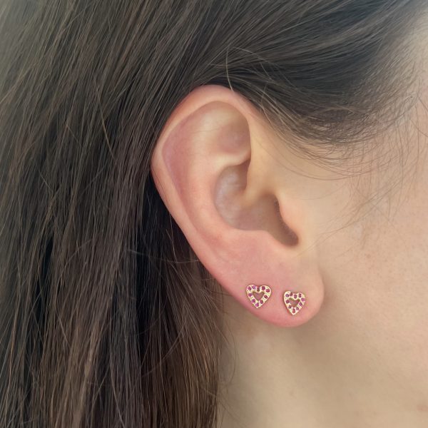 wearing the tiny open heart stud earrings in 14k yellow gold with ruby gemstones