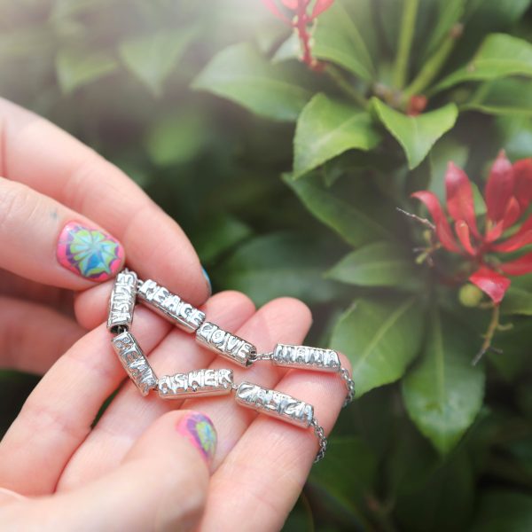 holding-the-tiny-gold-diamond-name-beads holding the platinum tiny name bead bracelets with diamonds