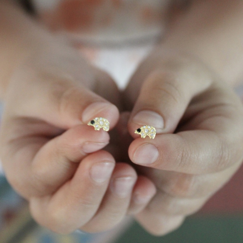 holding the tiny gold polar bear diamond stud earrings
