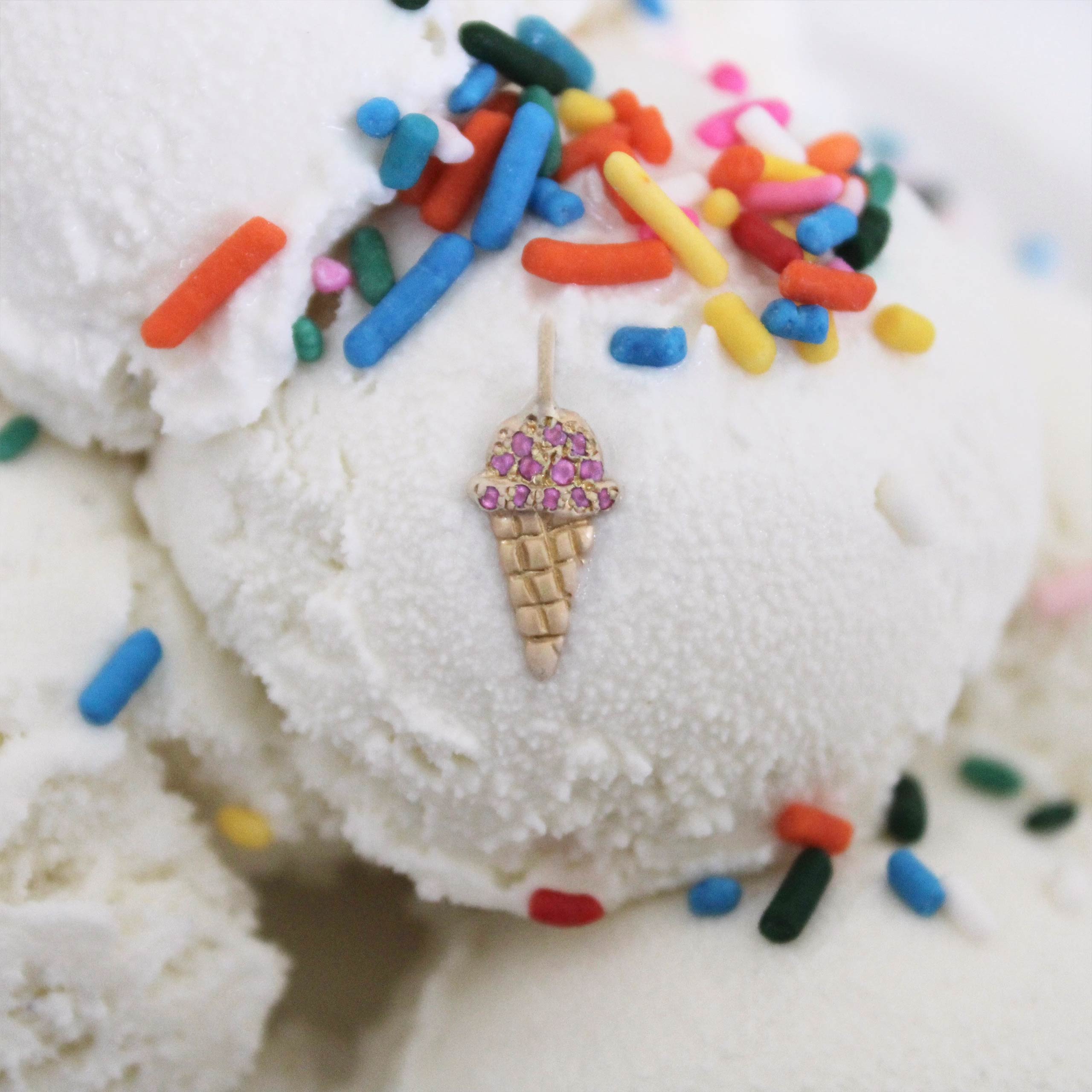 gold ice cream cone charm with pink diamonds on top of an ice cream scoop with sprinkles